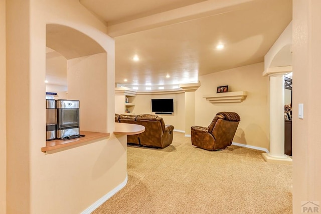 living area with carpet, decorative columns, arched walkways, and baseboards