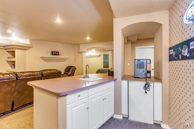 kitchen with white cabinets, a peninsula, arched walkways, and open floor plan