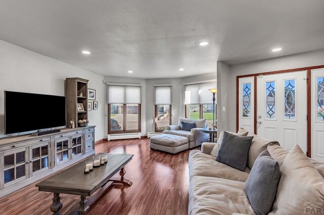 living area featuring baseboards, wood finished floors, baseboard heating, a baseboard heating unit, and recessed lighting