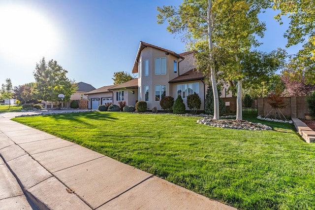 view of front of home featuring an attached garage, fence, a front lawn, and stucco siding