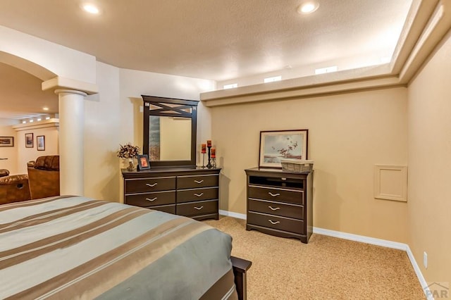 bedroom featuring arched walkways, a textured ceiling, light colored carpet, baseboards, and ornate columns