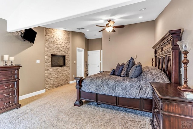 bedroom featuring lofted ceiling, a stone fireplace, light carpet, visible vents, and baseboards