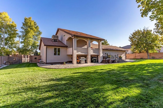 back of house with a yard, a fenced backyard, and stucco siding