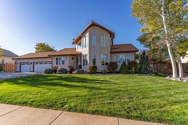 view of front of property with a garage, stucco siding, fence, and a front yard