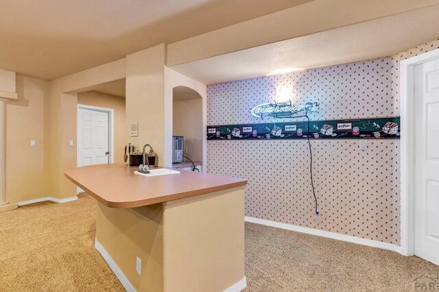 kitchen with light carpet, a sink, and baseboards