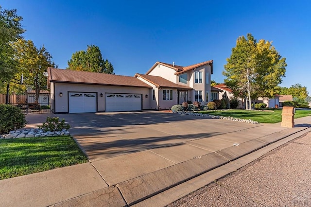 view of front of house featuring a tile roof, concrete driveway, an attached garage, a front yard, and fence