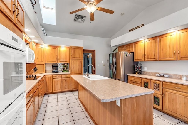 kitchen with a sink, visible vents, light countertops, stainless steel fridge with ice dispenser, and a center island with sink