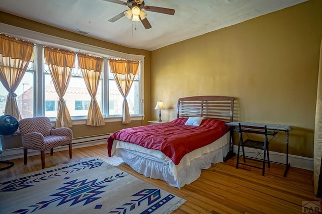 bedroom with visible vents, a ceiling fan, baseboards, and wood finished floors