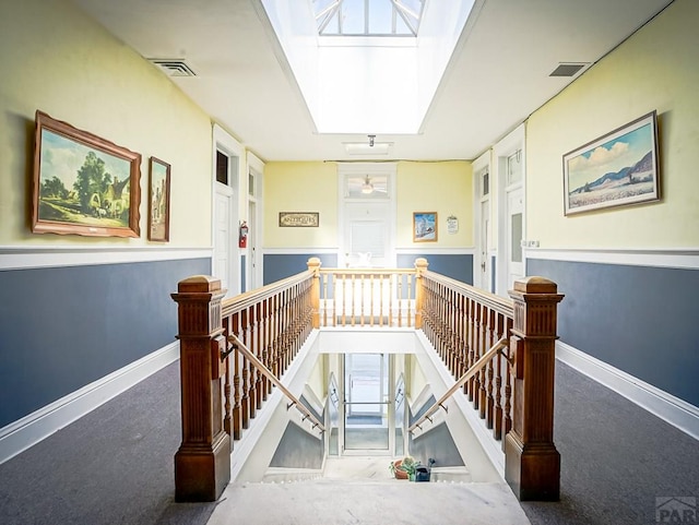 staircase featuring carpet flooring, visible vents, a skylight, and baseboards