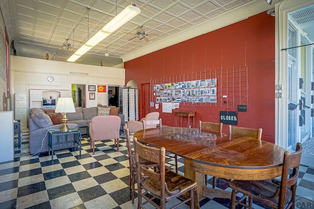 dining space featuring tile patterned floors, an ornate ceiling, wooden walls, and ceiling fan