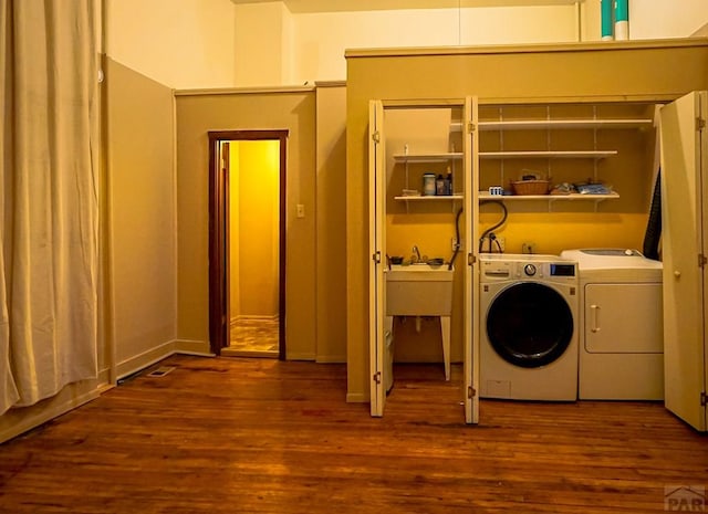 laundry area featuring a sink, wood finished floors, and washing machine and dryer