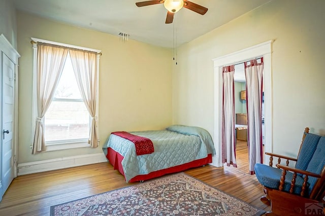 bedroom with visible vents, wood-type flooring, baseboards, and a ceiling fan