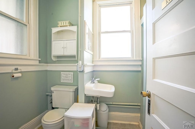 half bathroom featuring toilet, baseboards, and a sink