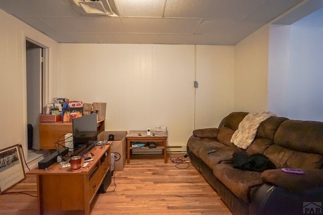 living area featuring light wood-style flooring, a paneled ceiling, and a baseboard radiator