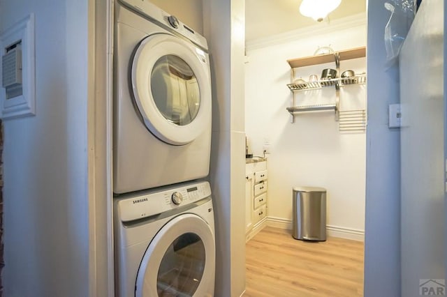 washroom with baseboards, ornamental molding, laundry area, light wood-style flooring, and stacked washer and clothes dryer