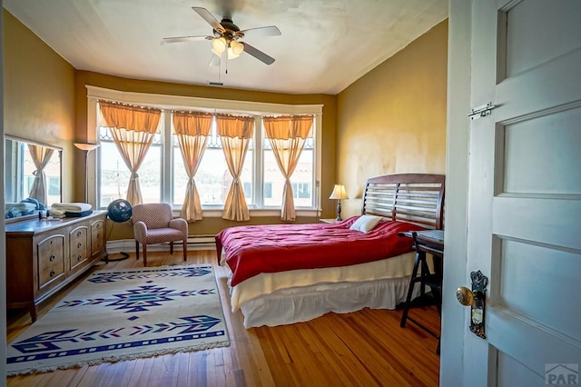 bedroom featuring multiple windows, wood-type flooring, ceiling fan, and vaulted ceiling