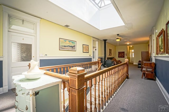 hall featuring visible vents, baseboards, a skylight, and carpet flooring