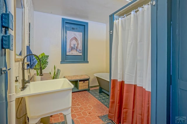 bathroom with tile patterned flooring, a freestanding tub, a shower with curtain, and a sink