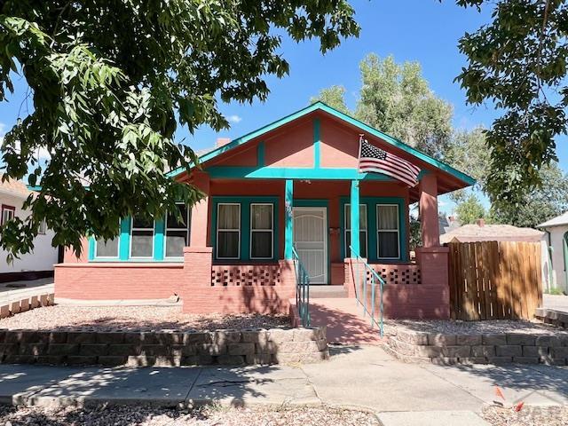 view of front of house with fence, a porch, and brick siding