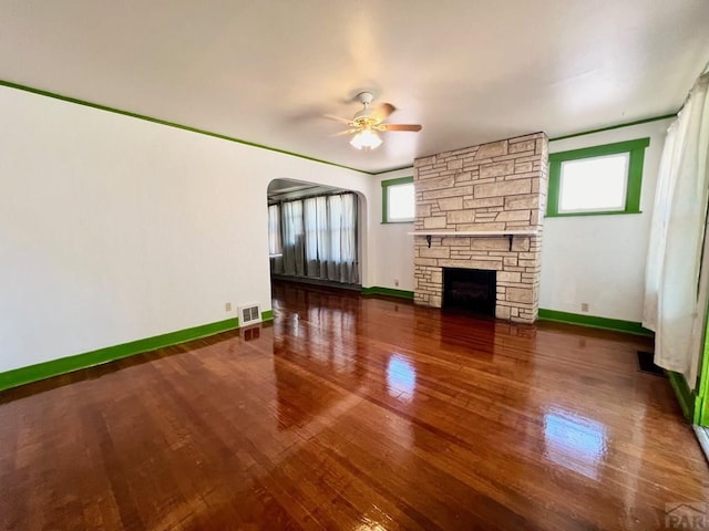 unfurnished living room with visible vents, plenty of natural light, a fireplace, and wood finished floors