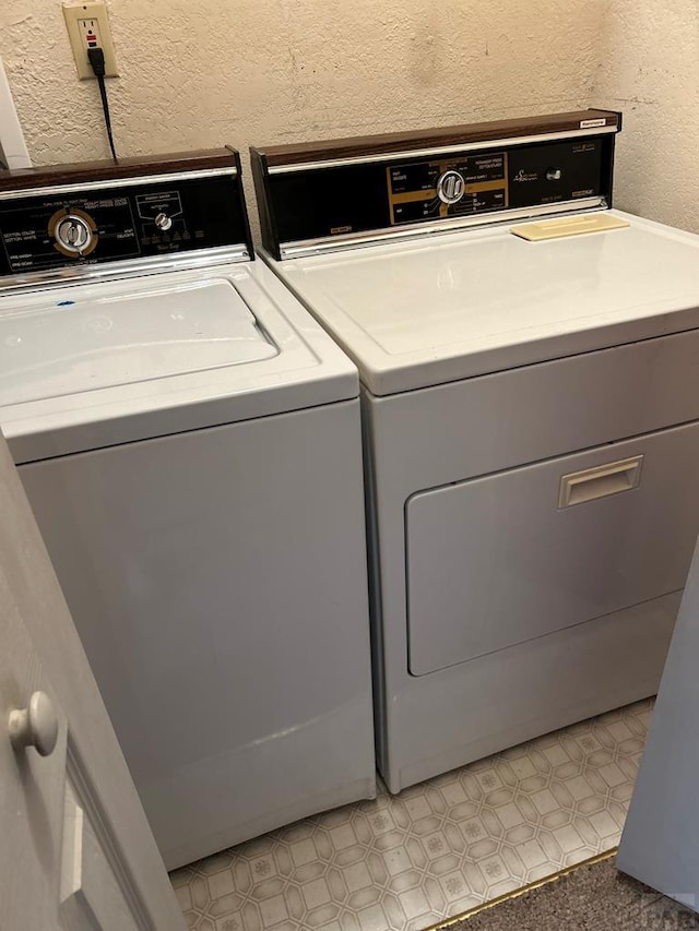 clothes washing area featuring laundry area, separate washer and dryer, and a textured wall
