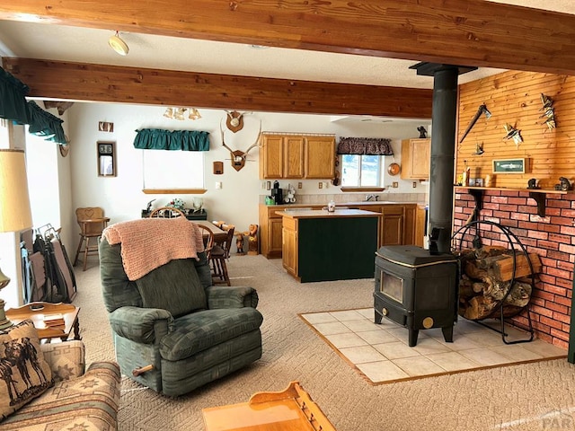 living area featuring a wood stove, light carpet, and beam ceiling