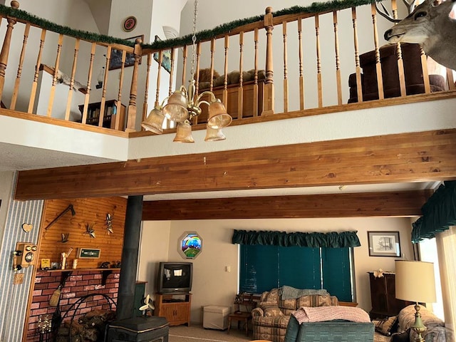 living room with a wood stove, beamed ceiling, and a towering ceiling