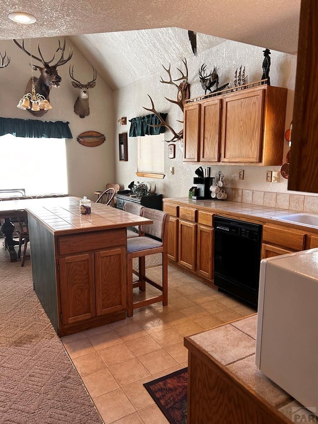 kitchen with brown cabinets, tile counters, lofted ceiling, a textured ceiling, and dishwasher