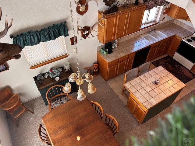 kitchen with tile countertops, brown cabinetry, and black dishwasher