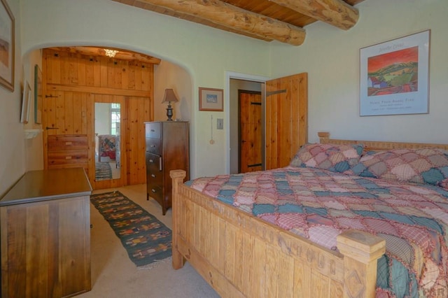 carpeted bedroom featuring arched walkways, beamed ceiling, and wood ceiling