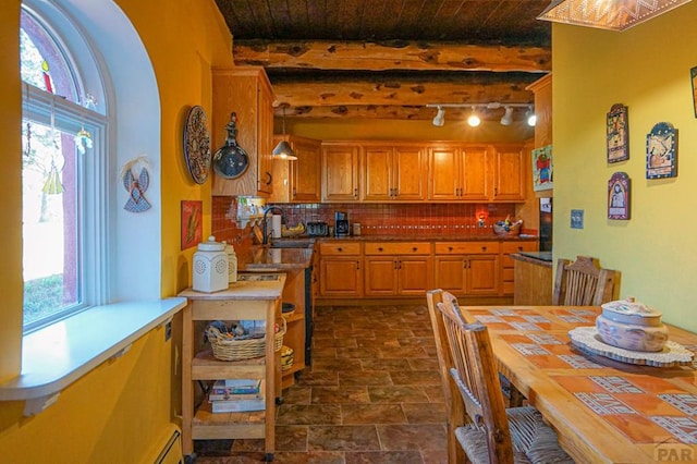 kitchen featuring pendant lighting, backsplash, stone finish floor, a sink, and wooden ceiling