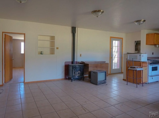 kitchen featuring built in shelves, a breakfast bar area, light tile patterned flooring, white appliances, and light countertops