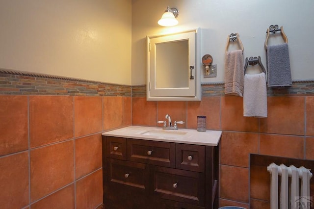 bathroom with tile walls, vanity, and radiator