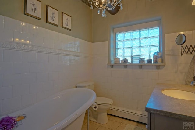 bathroom featuring tile patterned floors, a freestanding bath, vanity, a baseboard heating unit, and tile walls