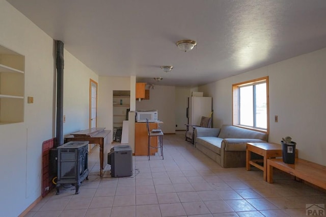 living area with a wood stove and light tile patterned floors