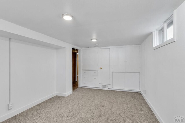 below grade area with light carpet, visible vents, and baseboards