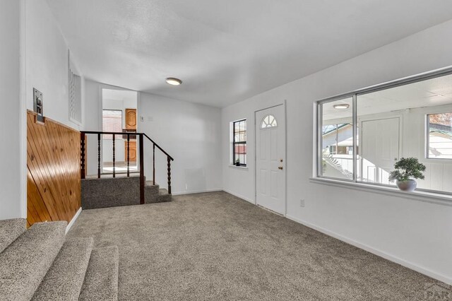 entrance foyer featuring carpet flooring, baseboards, and stairs