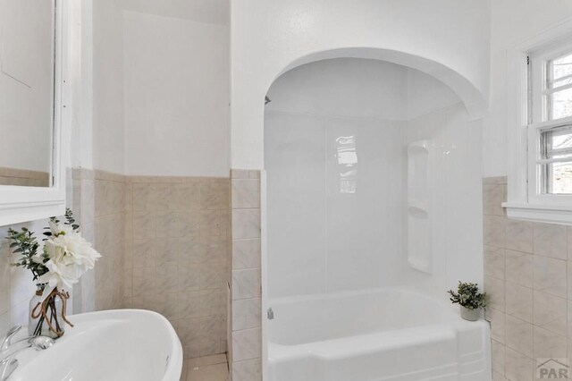 full bath with bathtub / shower combination, wainscoting, a sink, and tile walls