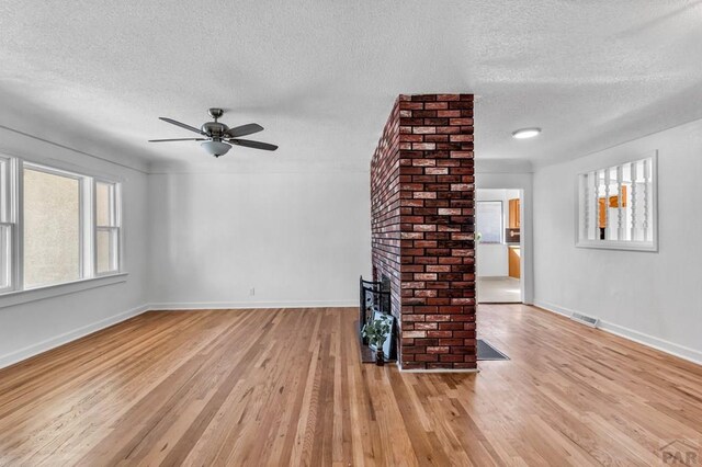 unfurnished living room featuring baseboards, light wood-type flooring, visible vents, and a brick fireplace