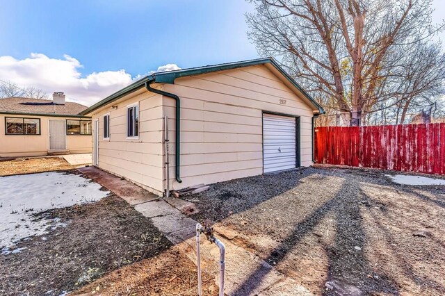 detached garage featuring gravel driveway and fence