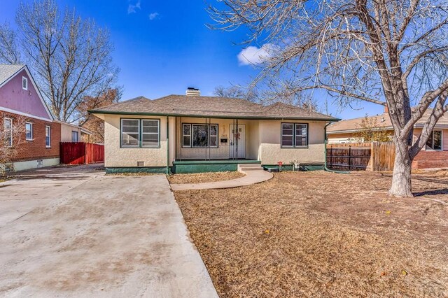 ranch-style house with a chimney, fence, and stucco siding