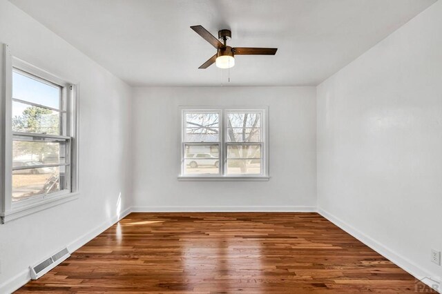 spare room featuring dark wood-type flooring, visible vents, and baseboards