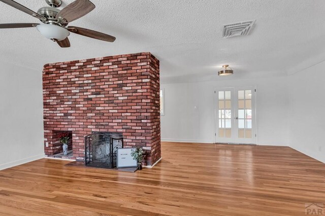 unfurnished living room featuring a textured ceiling, ceiling fan, light wood-type flooring, and visible vents