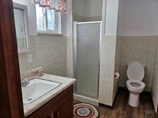 1640 Wabash Ave, Pueblo, CO 81004 - full bathroom featuring tile walls, a stall shower, vanity, toilet, and wood finished floors