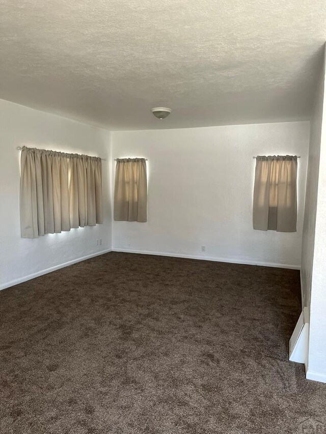 1640 Wabash Ave, Pueblo, CO 81004 - spare room with dark colored carpet, a textured ceiling, and baseboards