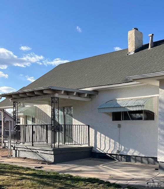 1640 Wabash Ave, Pueblo, CO 81004 - back of house featuring stucco siding, a chimney, and roof with shingles