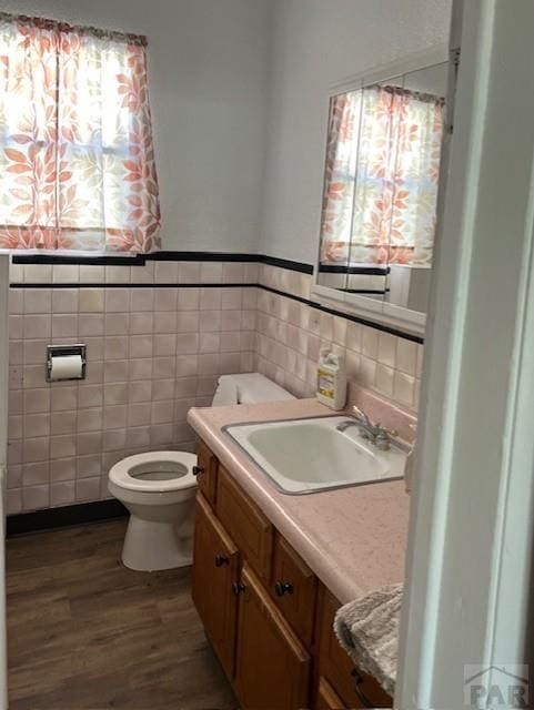 1640 Wabash Ave, Pueblo, CO 81004 - bathroom featuring vanity, tile walls, wood finished floors, toilet, and wainscoting