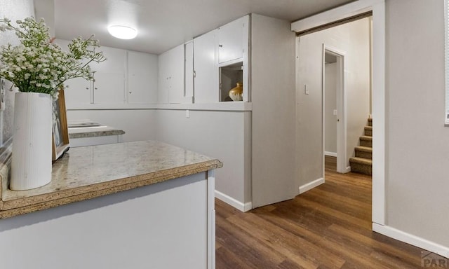 kitchen with dark wood-style floors, baseboards, white cabinetry, and light countertops