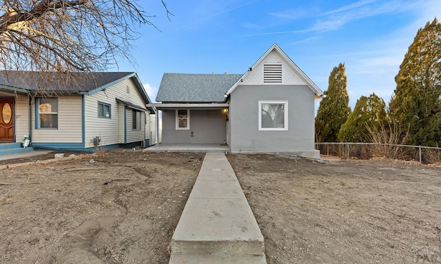 bungalow-style home featuring roof with shingles and fence