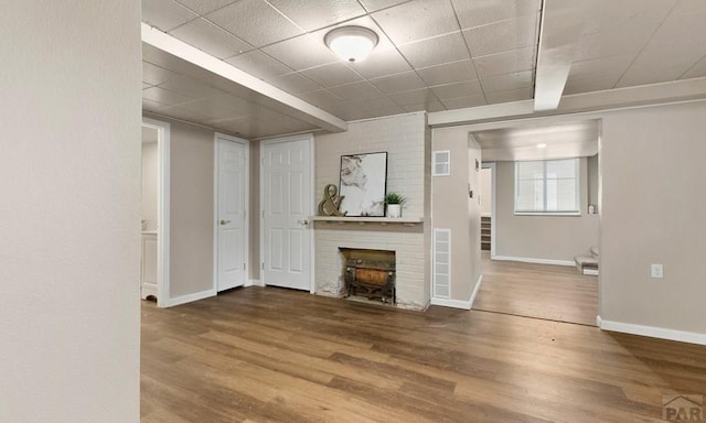 interior space featuring baseboards, a drop ceiling, and wood finished floors